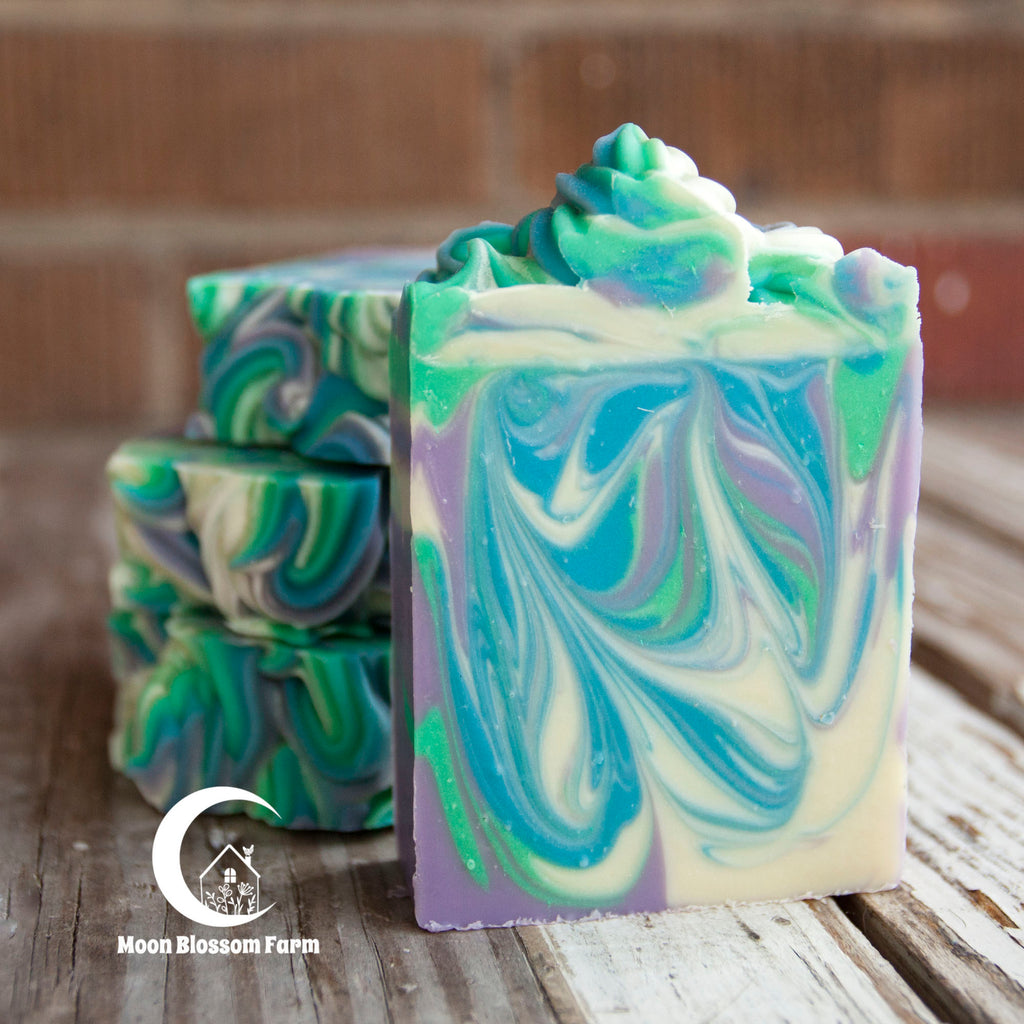 Colorful swirled soap bars on a wooden surface with 'Moon Blossom Farm' logo.