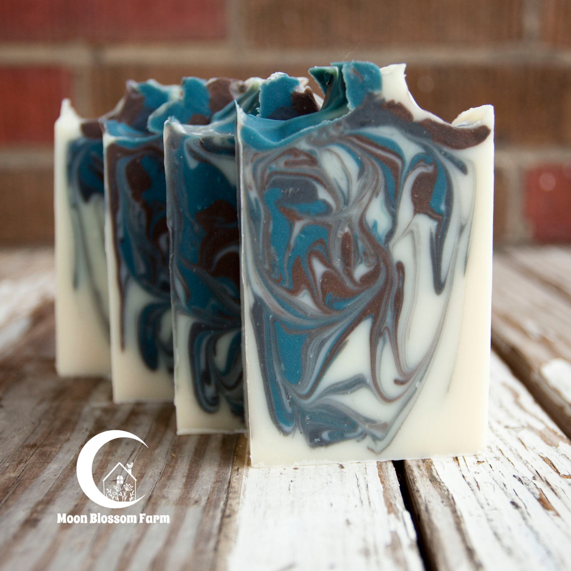 Marbled soap bars on a wooden surface with 'Moon Blossom Farm' branding.