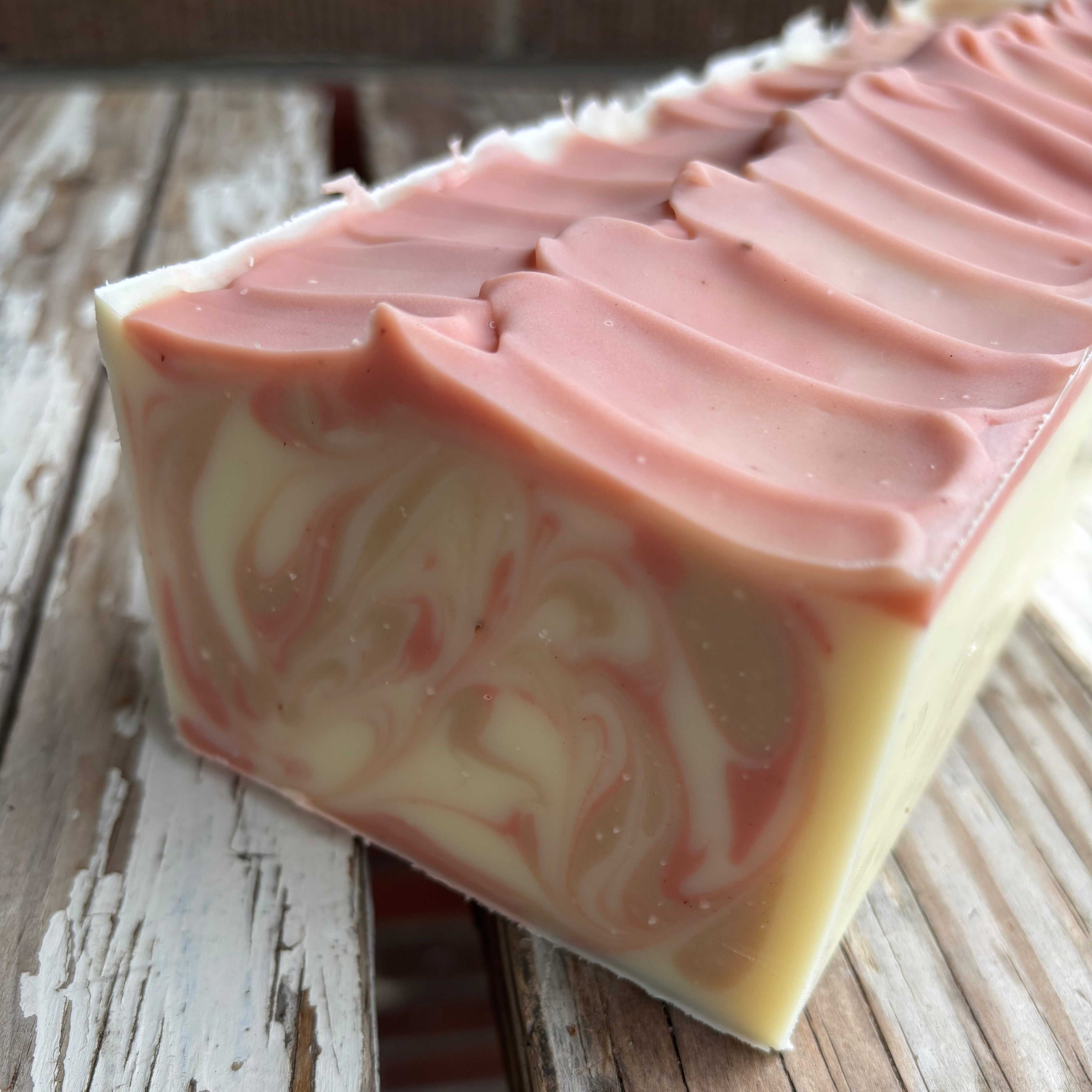 Swirled pink and white soap bar on a rustic wooden surface