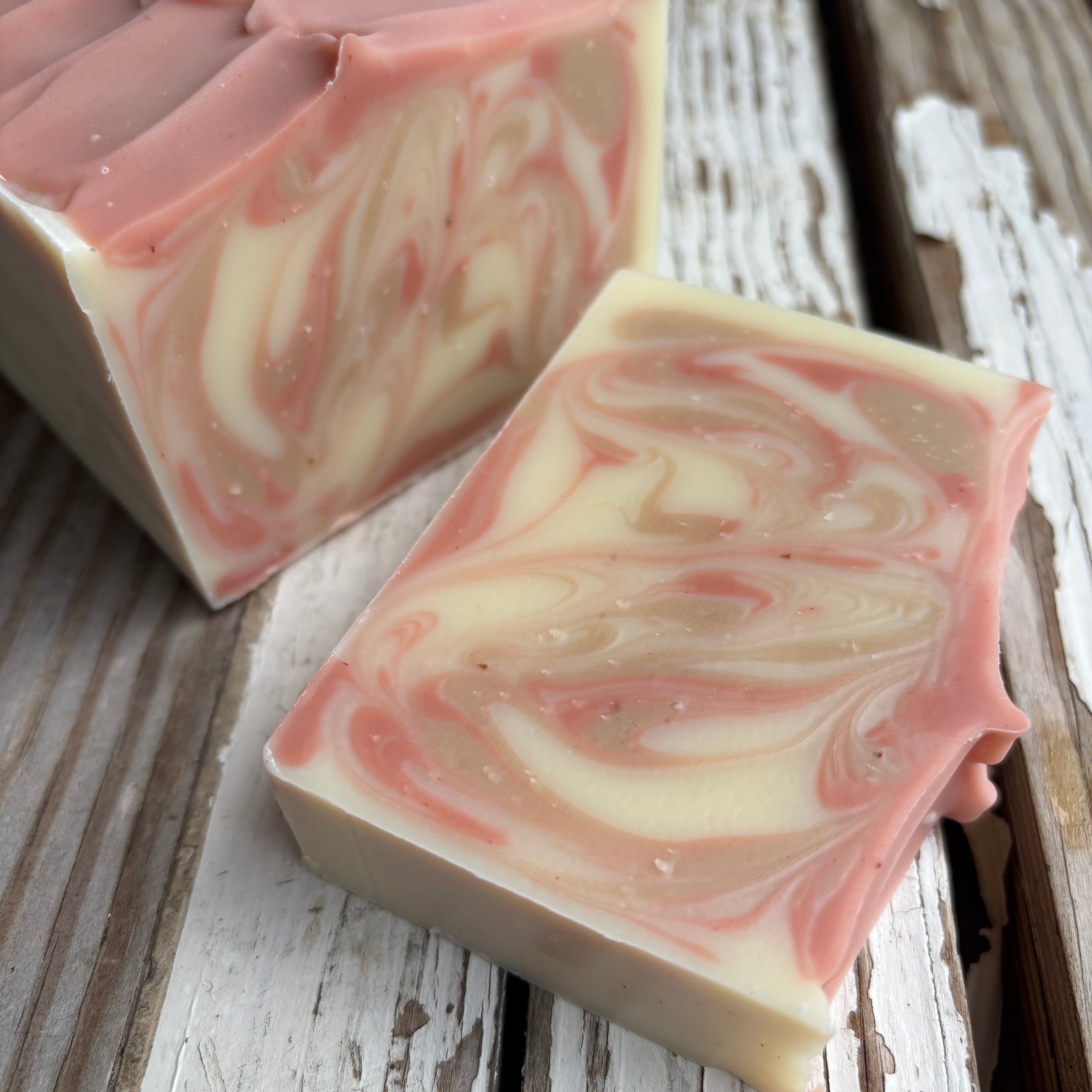 Two bars of soap with pink and white swirls on a wooden surface