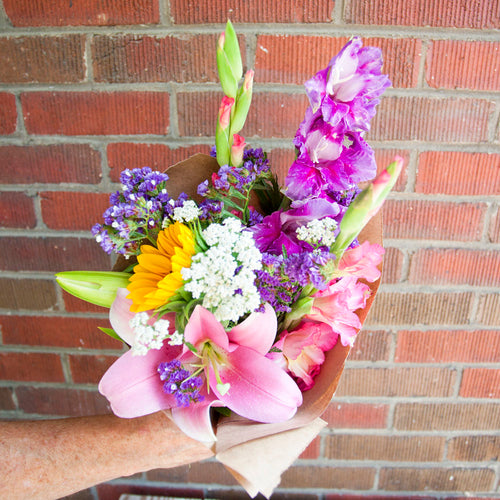Bouquet of colorful flowers held against a brick wall