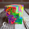 Stack of colorful swirled soap bars on a wooden surface with 'Moon Blossom Farm' branding.